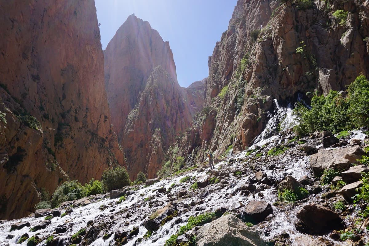 The springs of Taghia on the walk-in from the village, with the Taoujdad tower in the gap behind: the path follows the stream up to here.
