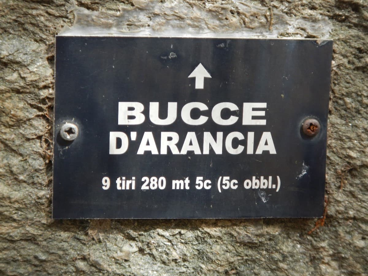 The metal plaque at the start: 'Bucce d'Arancia, 9 tiri 280 mt 5c', with an arrow pointing up (November 2015).