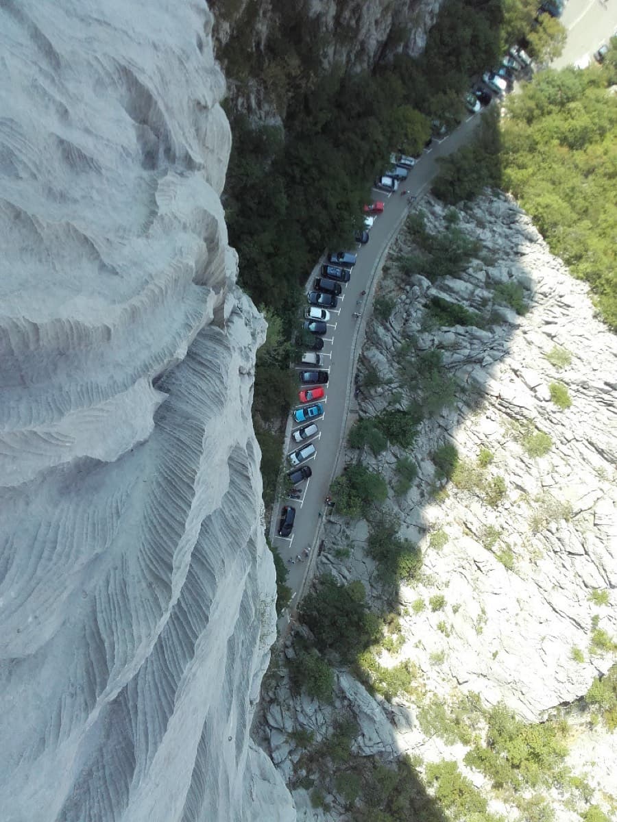 Looking down from the route onto the roadside car park in the gorge: the wall rises directly above the parked cars.