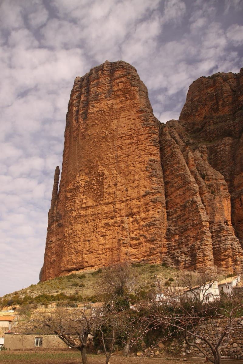 El Pisón from the edge of the village, with the thin spire of El Puro against its left side. The approach walks up through the village to the foot of the tower.