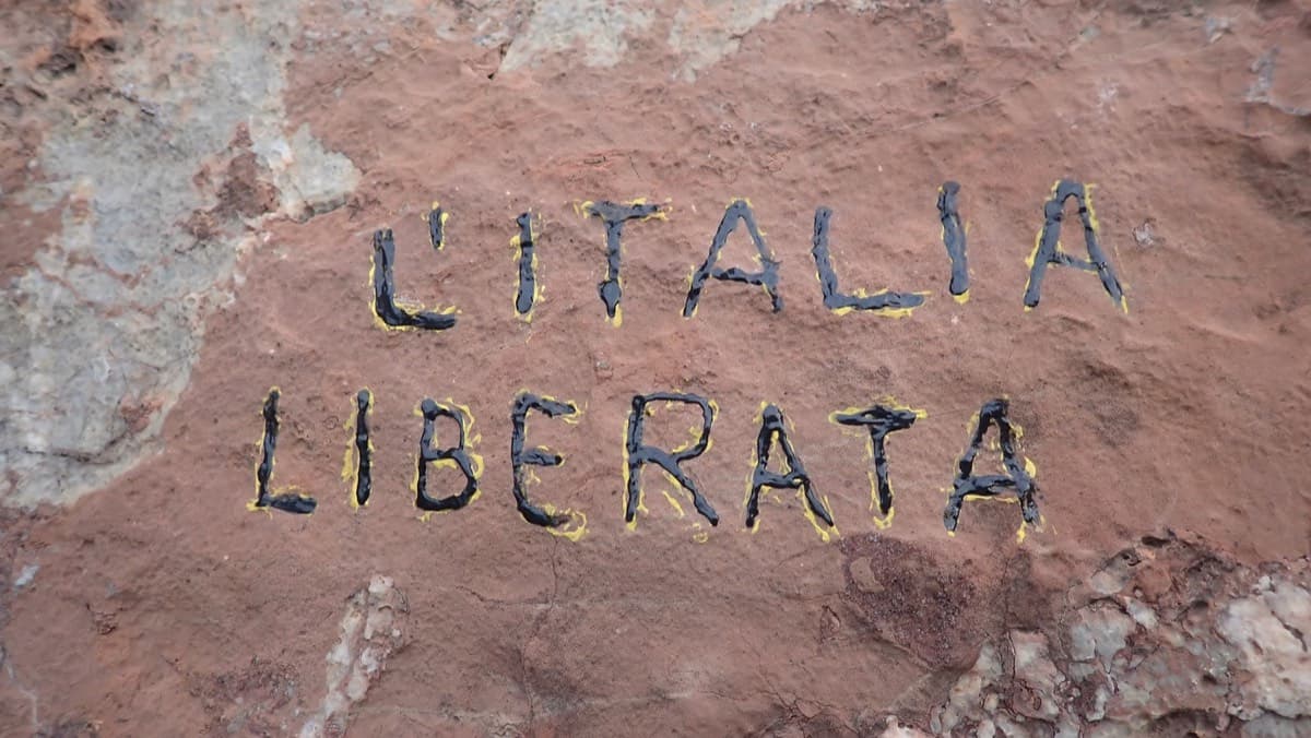 The route name painted in black on red rock at the base.