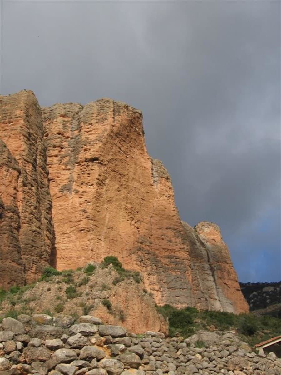 La Visera seen from the top of the village, behind a dry-stone wall; walk straight up to the foot of the face.