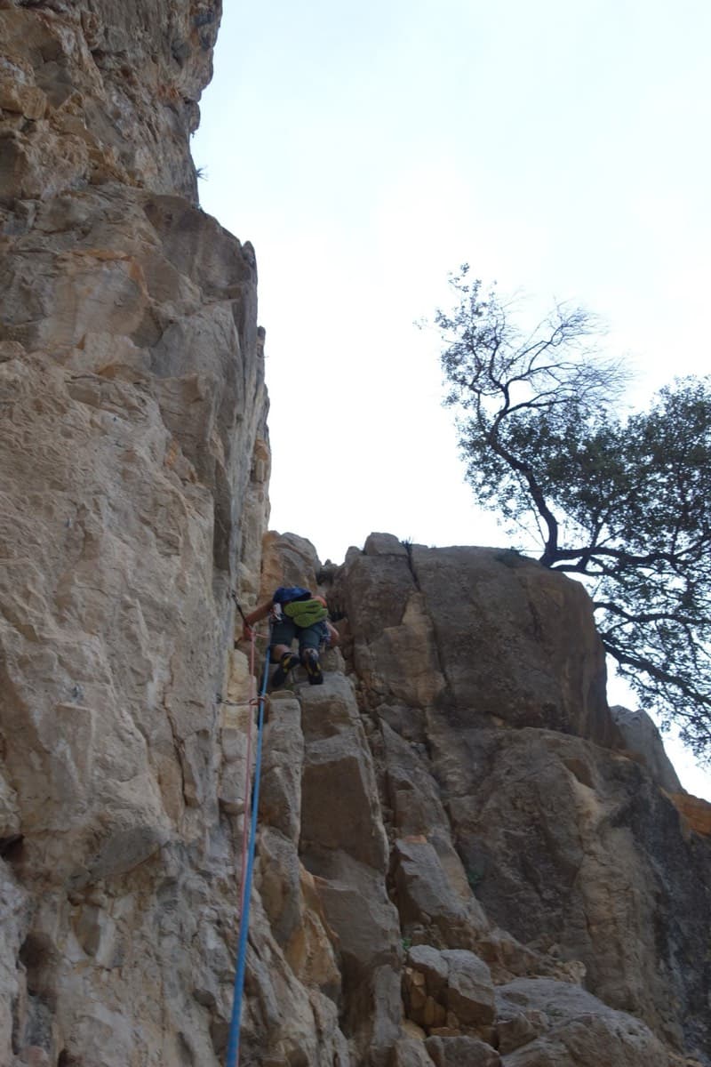 The start of the route: a corner with a tree above it, right of the Poema de Roca cave.