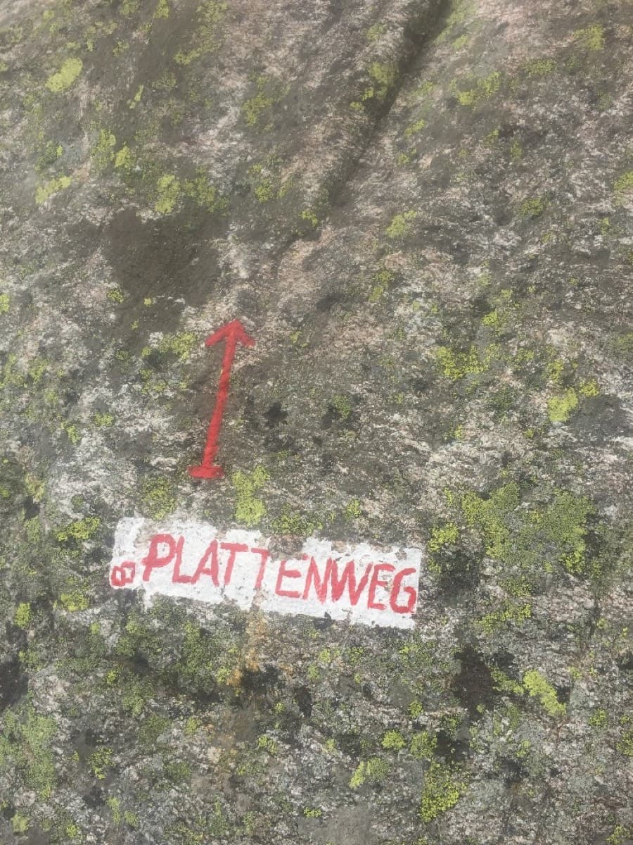 The start: 'PLATTENWEG' painted in red on white, with a red arrow, at the base of the slab.