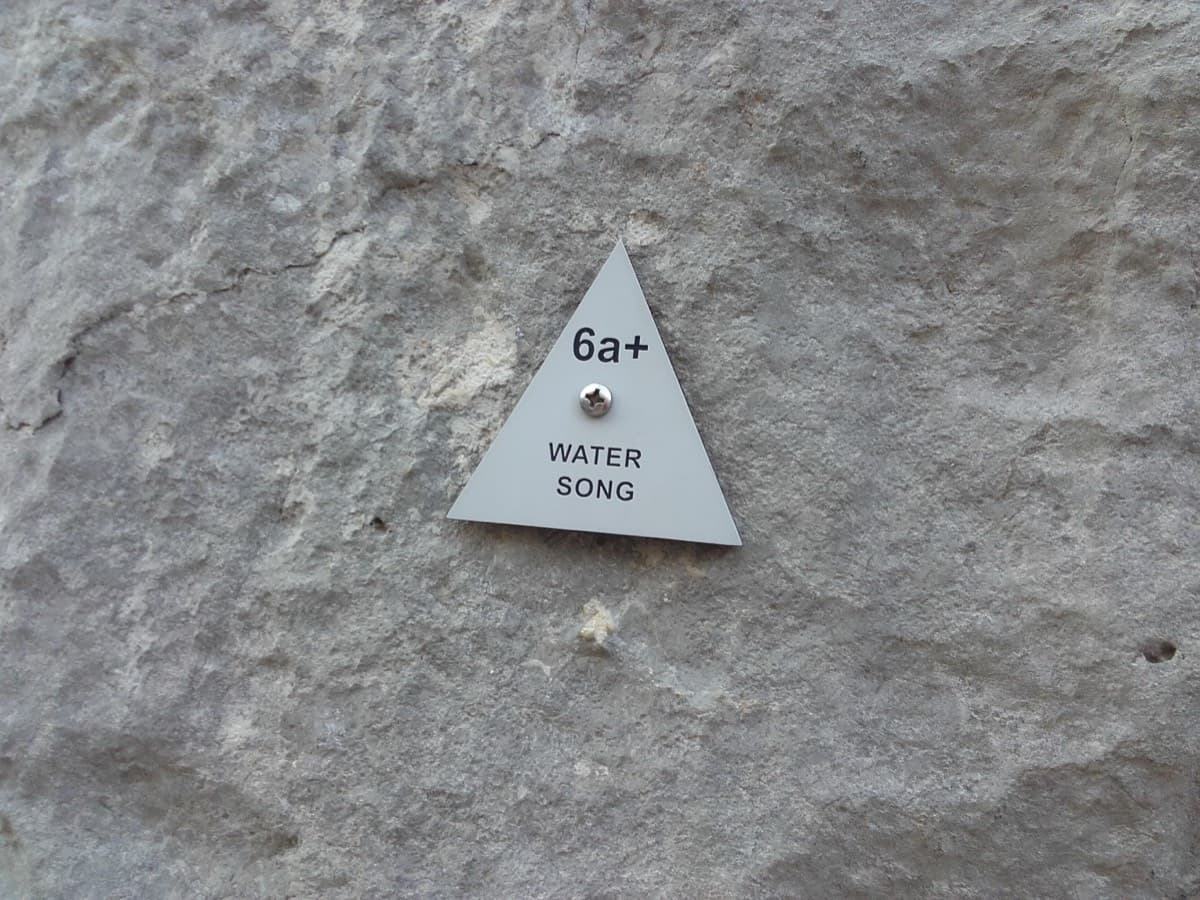 The small triangular plate at the start, reading "6a+ Water Song".