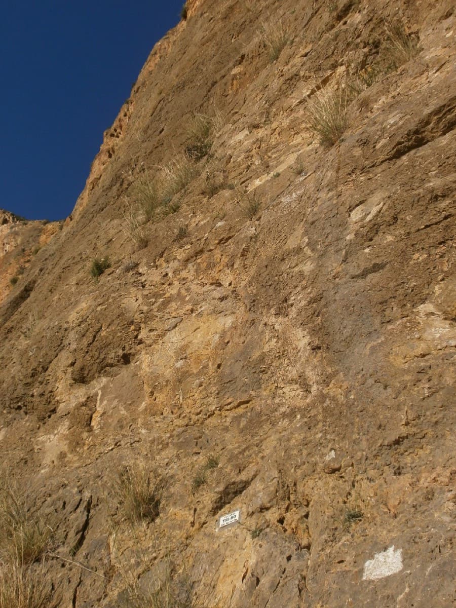 The foot of Tribo on La Pancha, Redován, with the route's name plate on the rock.