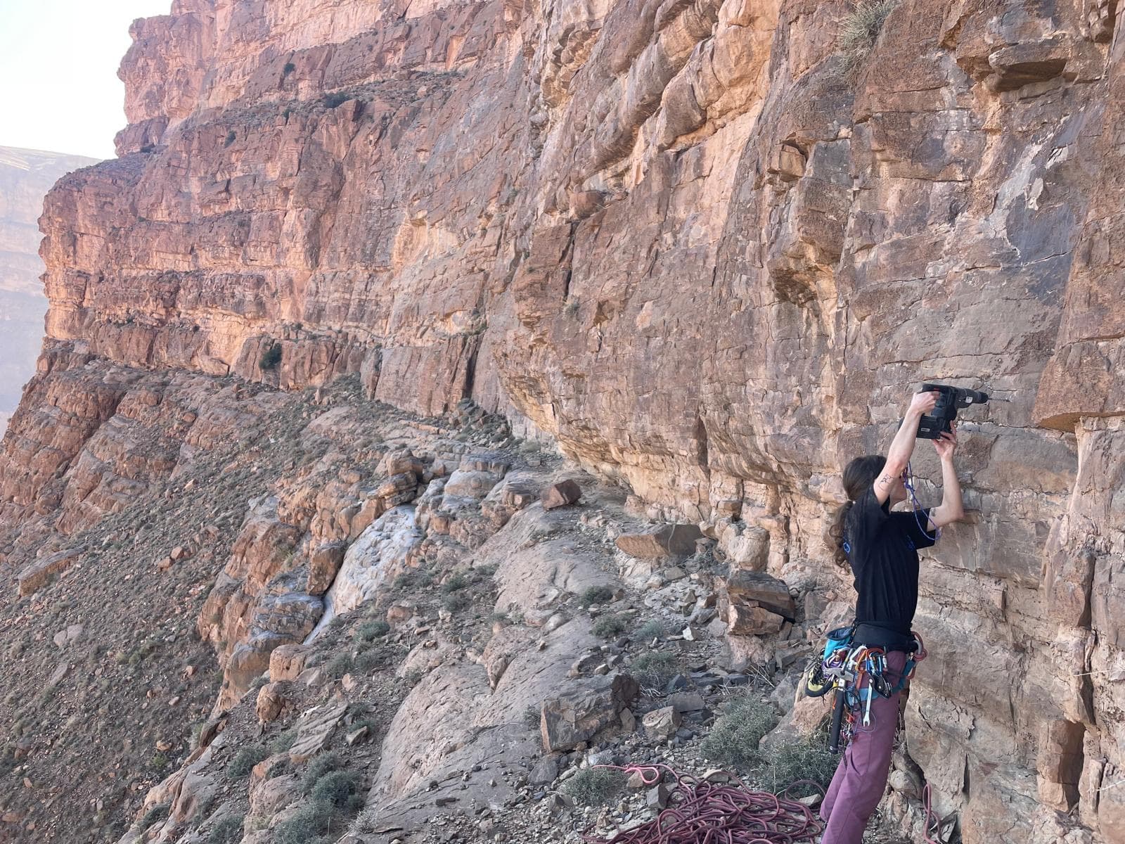 Placing the first bolt of pitch 3 of Allah bri des toits, with the Paroi Tizzarouine running away behind.