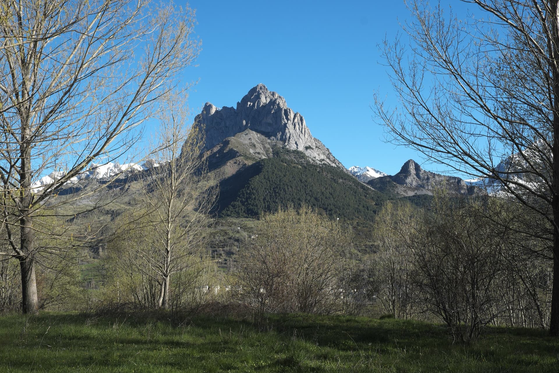 The twin limestone summits of Peña Foratata above the forest, seen from Sallent de Gállego in spring.