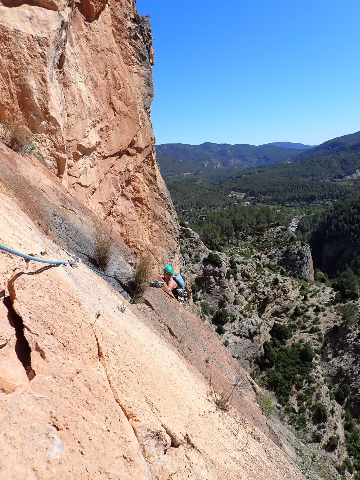 Red slabs of the Los Calpes sector on Monsieur, with the Maimona gorge and the pine hills of Montanejos behind.