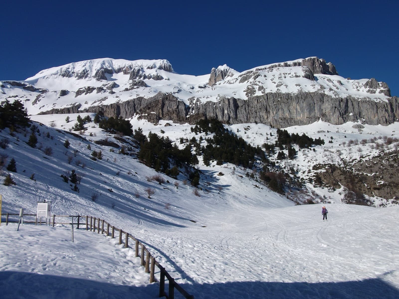 Snow-covered limestone cliff bands above the Lizara plateau, photographed from the Refugio de Lizara in winter.