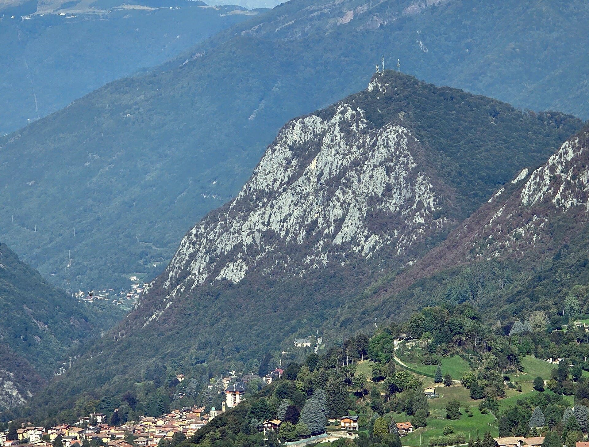 The south side of the Zucco dell'Angelone above Barzio, seen from the Zucco della Croce: the pale limestone spurs (speroni) that hold the multipitch routes run down from the antenna-topped summit. Condorpass is on the fourth spur; individual spurs are not labelled here.